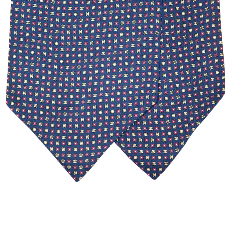 Dettaglio delle due pale di un ascot in seta blu navy con motivi quadrati alternati rosso rubino e giallo oro