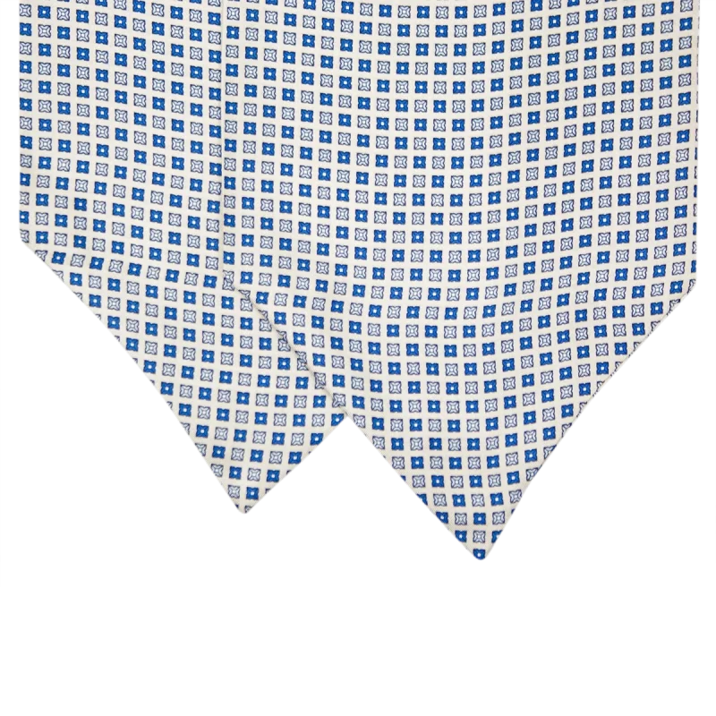 Primo piano delle due pale di un ascot in seta grigio perla con piccoli motivi quadrati alternati in blu cobalto e blu navy