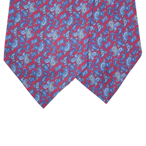 Dettaglio delle due pale di un ascot in seta rossa con motivi paisley blu e azzurri e piccoli particolari beige