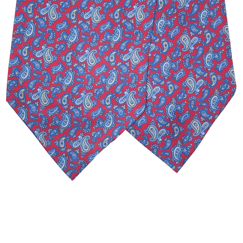 Dettaglio delle due pale di un ascot in seta rossa con motivi paisley blu e azzurri e piccoli particolari beige