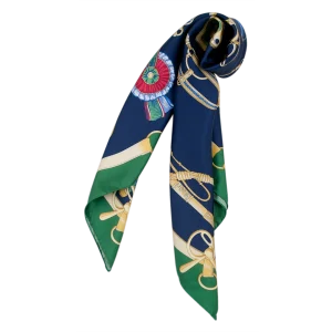 Inquadratura ravvicinata della fantasia equestre che evidenzia i dettagli delle briglie, delle decorazioni dorate e degli accessori sul fondo blu navy, con il bordo verde bosco. FH07 foulard da donna in seta blu navy e verde bosco piegato con estremità pendenti e motivi equestri