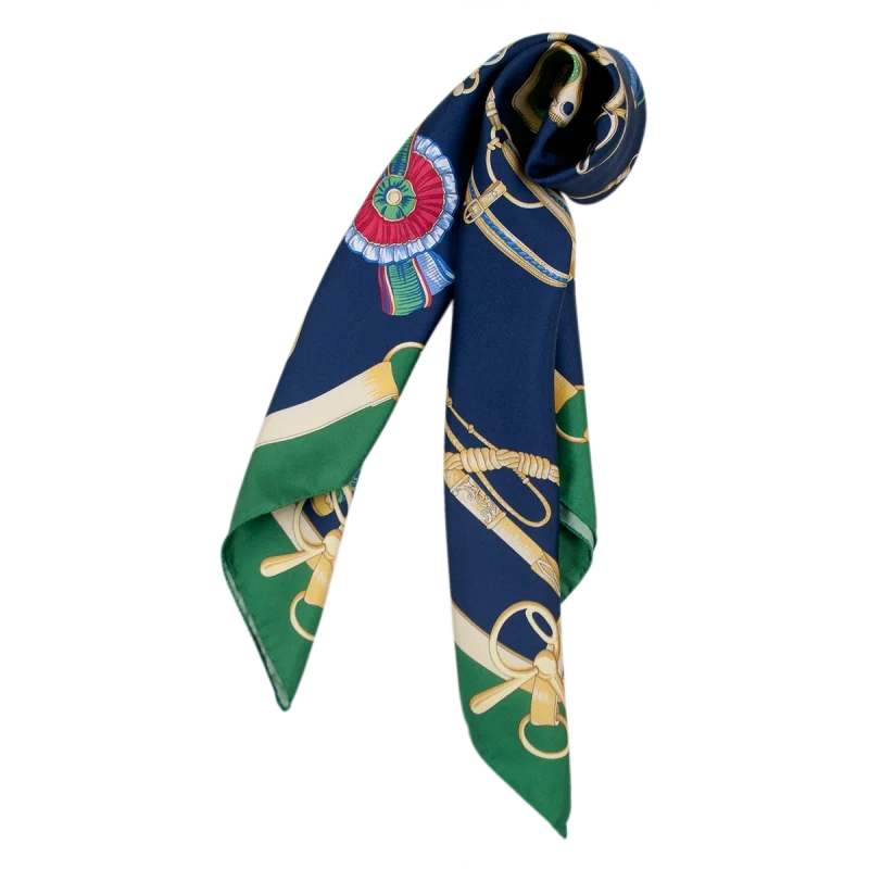 Inquadratura ravvicinata della fantasia equestre che evidenzia i dettagli delle briglie, delle decorazioni dorate e degli accessori sul fondo blu navy, con il bordo verde bosco. FH07 foulard da donna in seta blu navy e verde bosco piegato con estremità pendenti e motivi equestri