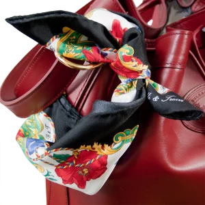 Foulard piccolo in seta con bordo nero e fantasia floreale annodato su borsa bordeaux in pelle