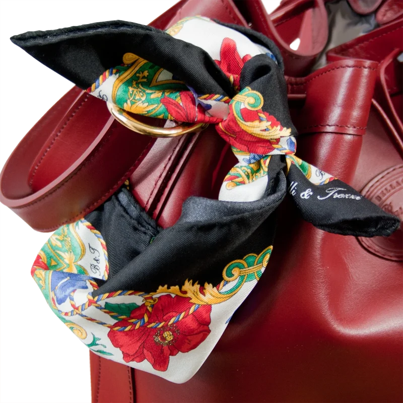 Foulard piccolo in seta con bordo nero e fantasia floreale annodato su borsa bordeaux in pelle