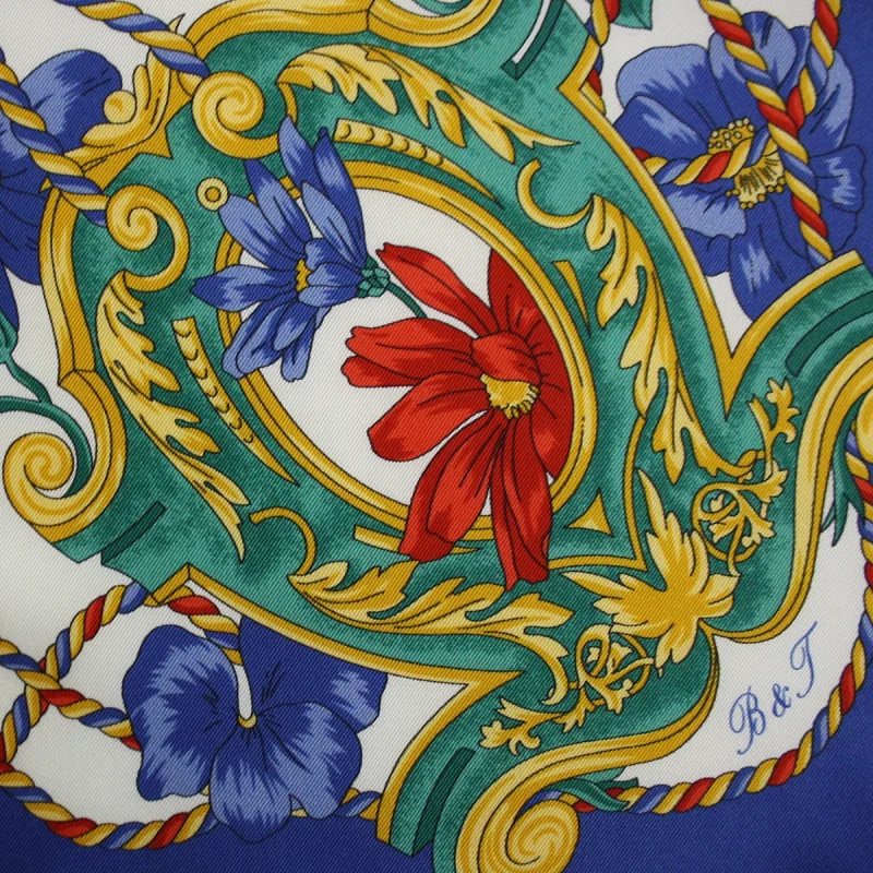 dettaglio foulard in seta con decori verdi e dorati fiori rossi e blu