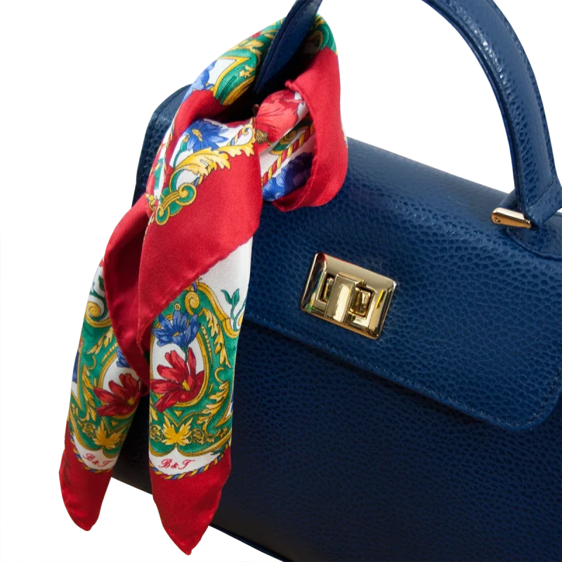 Foulard piccolo in seta rosso rubino con fantasia floreale utilizzato su borsa blu in pelle